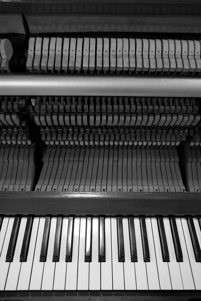 Black and white image of an upright piano showcasing keys and hammers.