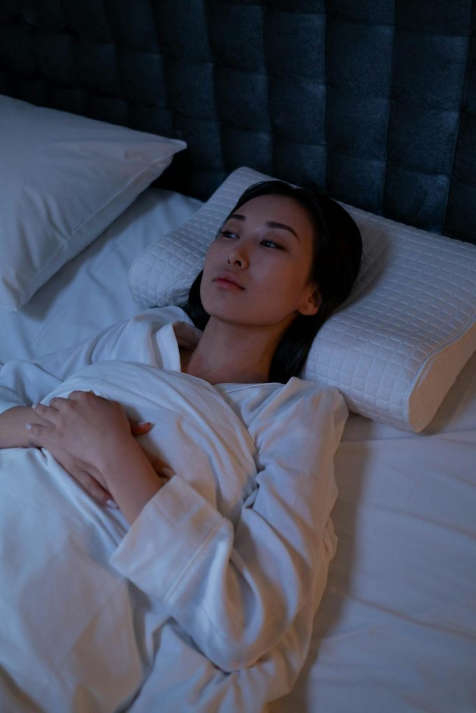 An Asian woman lying awake in bed, reflecting on her thoughts during a sleepless night.
