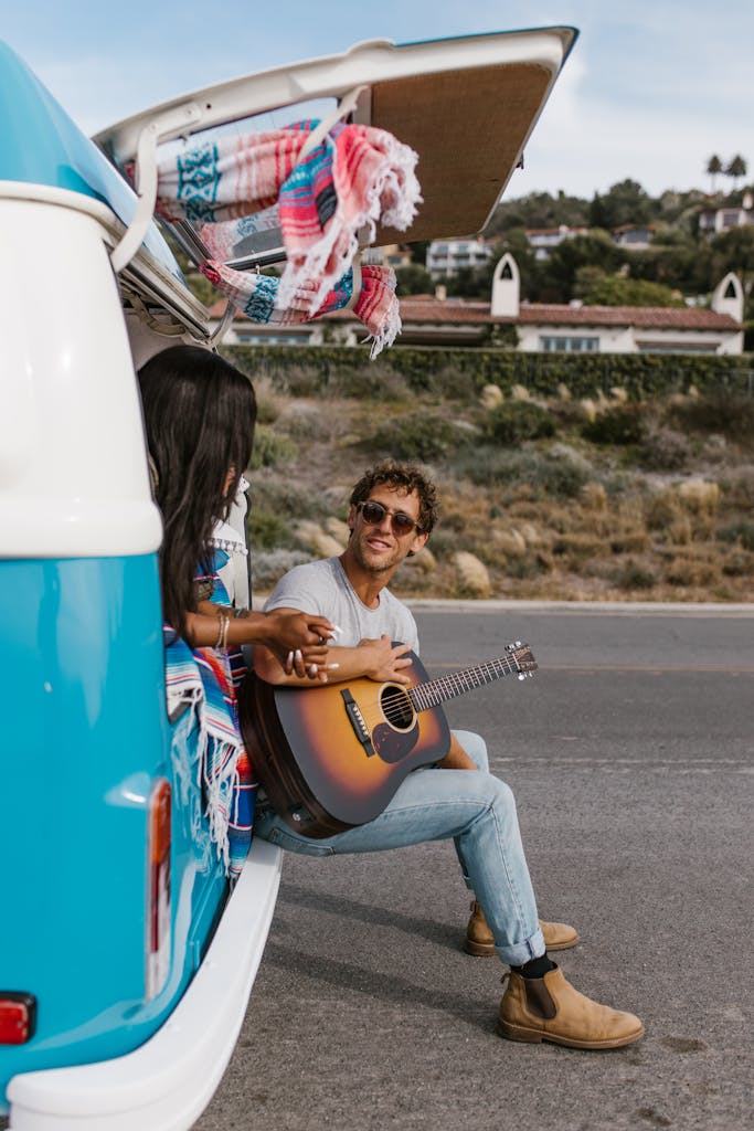 Couple enjoys a romantic moment on a road trip in a campervan with a guitar serenade.