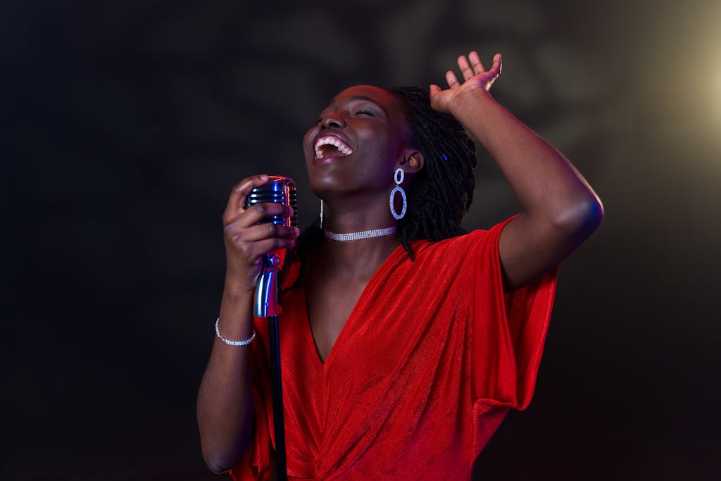 Energetic black female singer in red dress performing passionately on stage with a microphone.